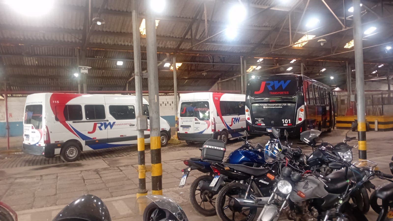 Frota de ônibus e vans da JRW Transportes na garagem